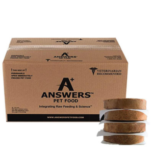 A cardboard box of Answers Pet Food raw frozen dog food patties displayed next to a small stack of round patties. The box features the Answers Pet Food logo, veterinary-recommended labeling, and branding emphasizing integrative raw feeding.