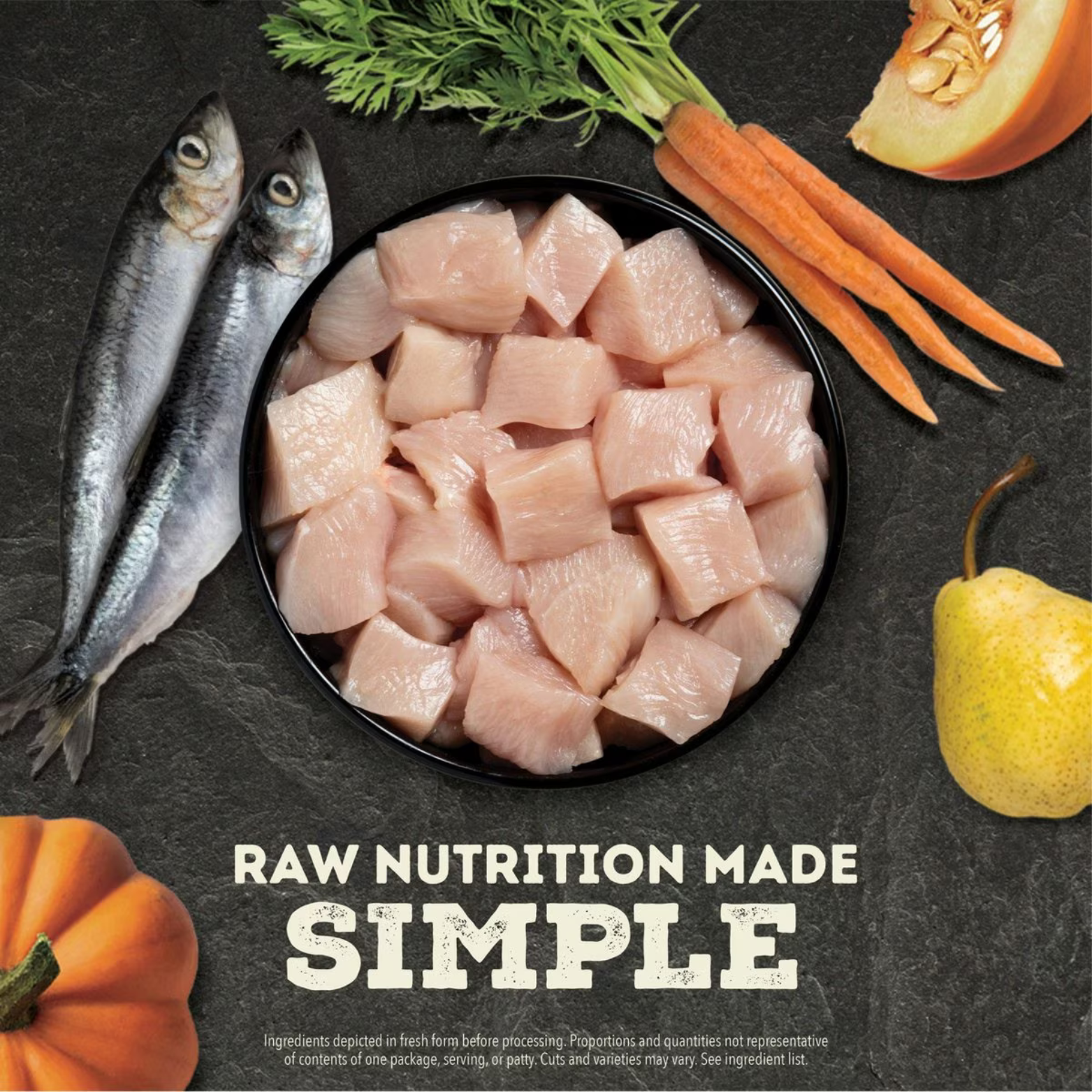 Photo of raw diced chicken pieces in a black bowl surrounded by fresh whole fish, carrots, pumpkin, and a pear on a dark stone background with the text 'Raw Nutrition Made Simple.'