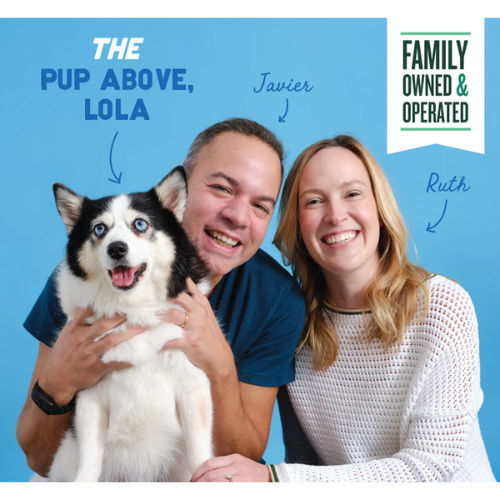 Photo of a couple smiling and posing with their fluffy black-and-white dog against a blue background, with handwritten labels identifying the dog as ‘Lola’ and the two people as the founders, and a banner reading ‘Family Owned & Operated.’