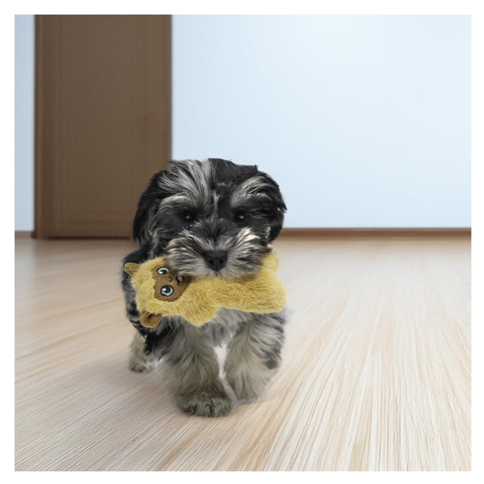 Small black-and-gray puppy walking indoors on a light wood floor while carrying a yellow llama plush dog toy in its mouth, with the toy’s face visible.