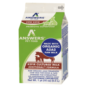 Front view of a green and white carton of Answers Pet Food raw organic A2 cow milk kefir for dogs. The packaging labels the product as a probiotic superfood made with organic A2 raw milk and kefir-cultured milk, intended as a supplemental feeding only. The carton contains one pint (16 ounces) and features branding, nutritional claims, and animal icons.
